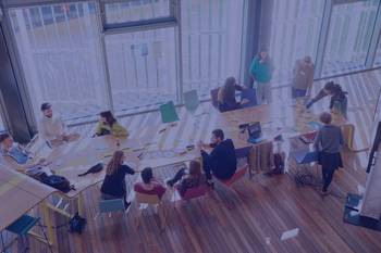 Vogelperspektive auf junge Menschen an einem Tisch in einer Workshopsituation, Bild mit blauem Overlay