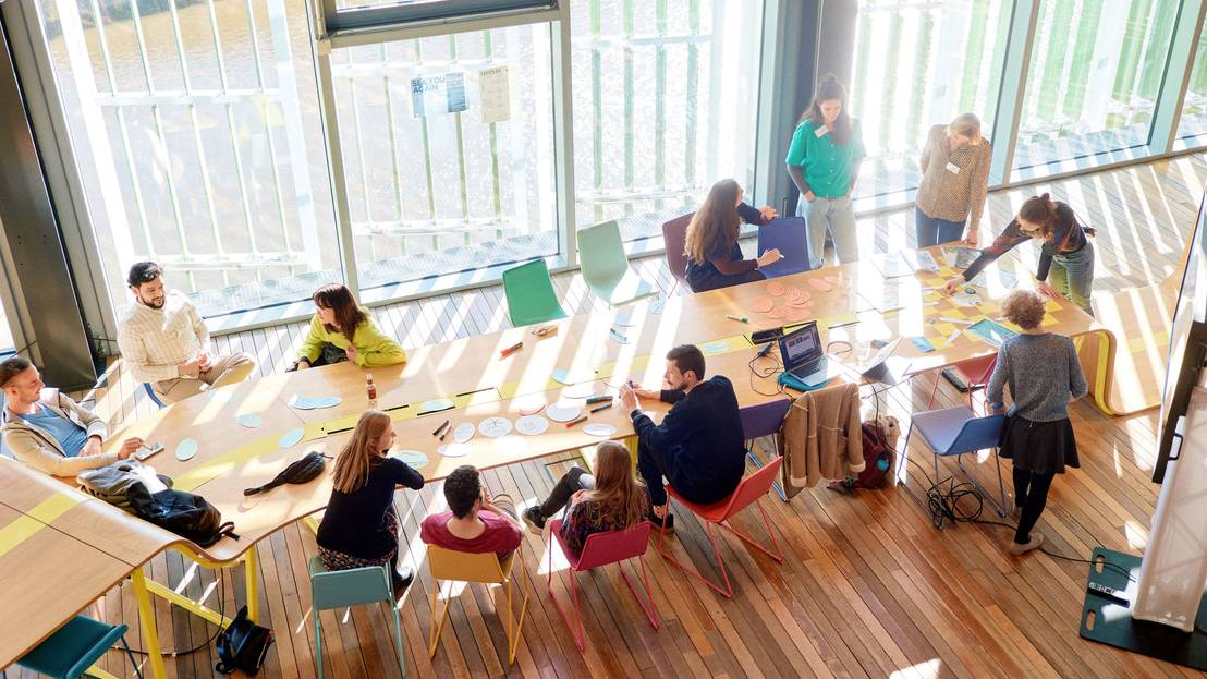 mehrere Teilnehmende sitzen an einem langen Tisch und arbeiten
