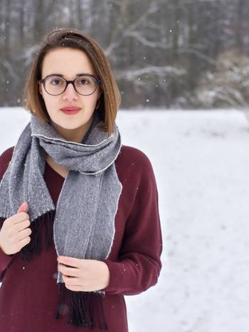Halbporträt der Komponistin Rachel C. Walker, mit Schal und Mantel in einer Winterlandschaft stehend